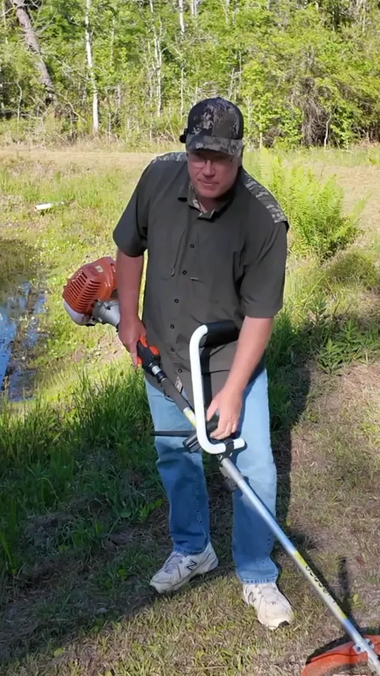 A customer using a string trimmer fitted with the Yeoman Handle